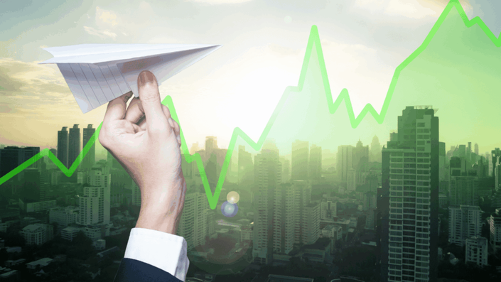 Imagen de una mano lanzando un avión de papel con un fondo urbano y una gráfica verde ascendente, simbolizando el crecimiento y éxito en fondos comunes de inversión.