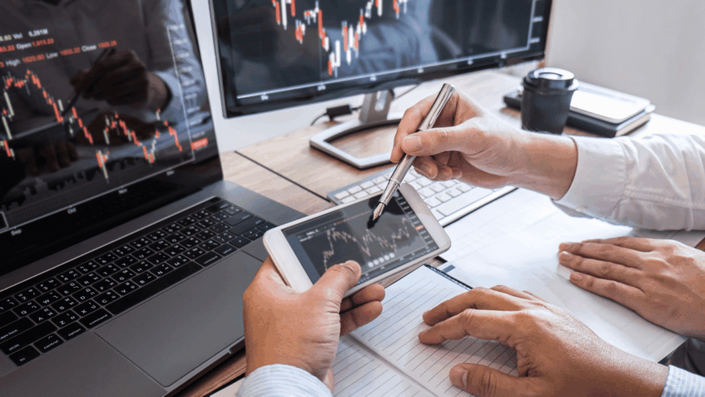 Personas analizando gráficos financieros en múltiples dispositivos como parte de estrategias de inversiones.