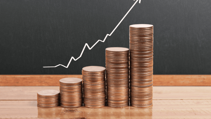 Pilas crecientes de monedas de cobre con una flecha blanca apuntando hacia arriba, simbolizando el crecimiento y las inversiones seguras.