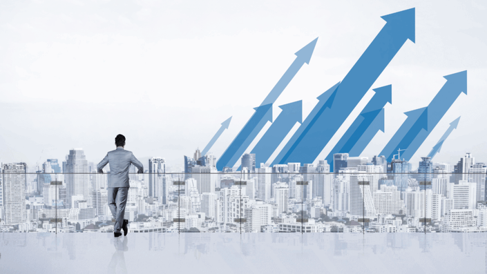 Empresario mirando un paisaje urbano con flechas azules ascendentes, simbolizando el crecimiento potencial de un portafolio de inversión y las oportunidades al aprender cómo invertir $100.