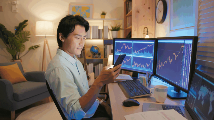 Inversor analizando gráficos financieros en múltiples pantallas y un smartphone en un entorno de oficina en casa, evaluando las Tendencias de inversión y sus riesgos.